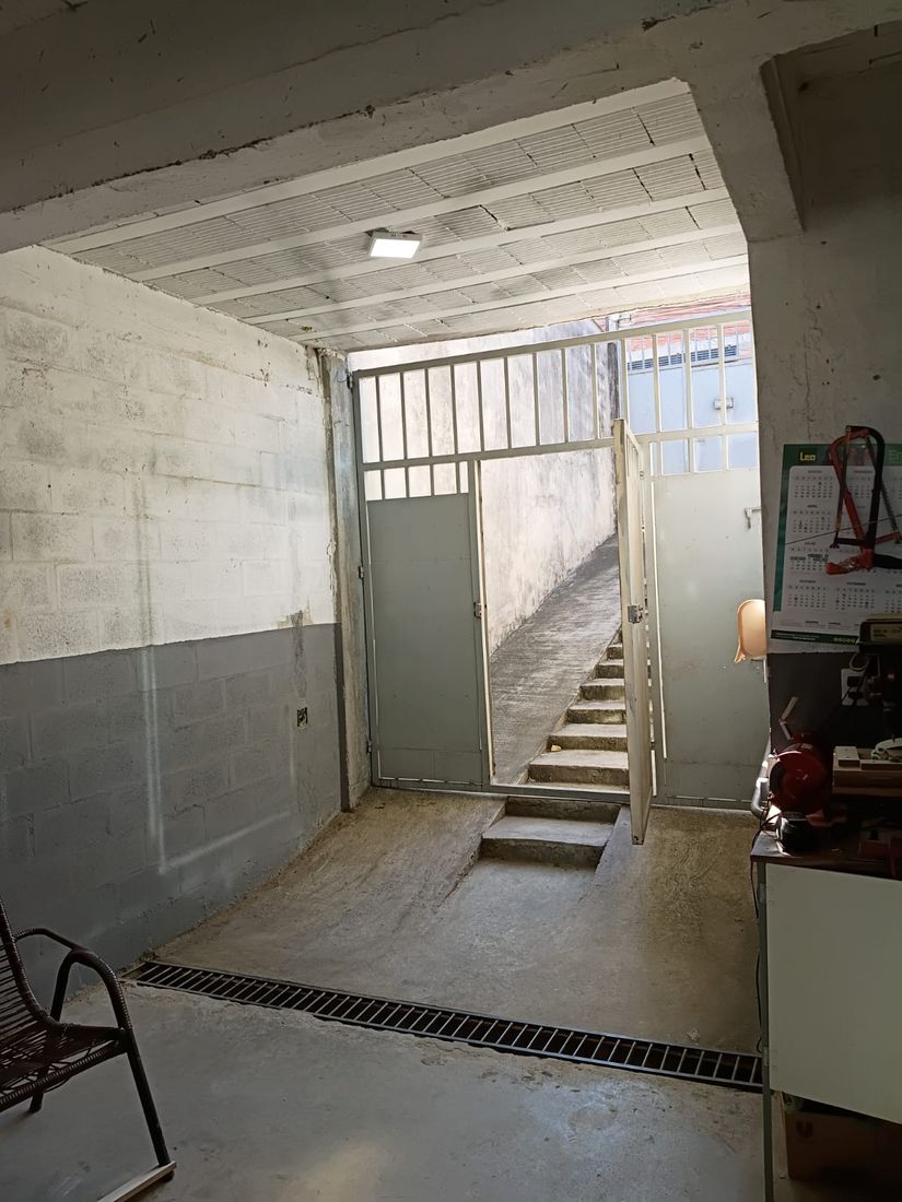 Corredor interno de acesso, com portão e escada